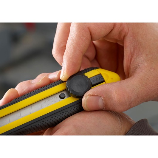 Close-up photo of STANLEY 0-10-417 utility knife with yellow and black handle, hand adjusting blade lock.