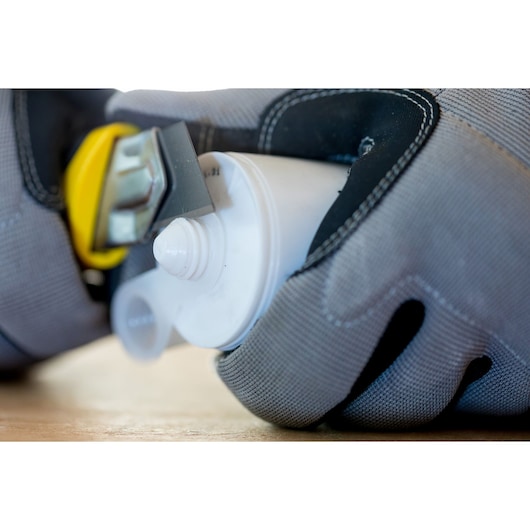 STANLEY 0-10-425 utility knife cutting plastic tube, close-up angled photo, handheld with gloves.