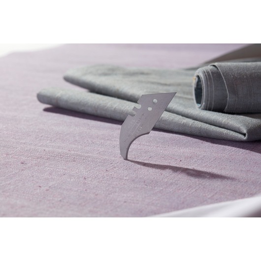 STANLEY 0-11-952 curved utility blade on purple fabric, two grey rolled textiles in background.