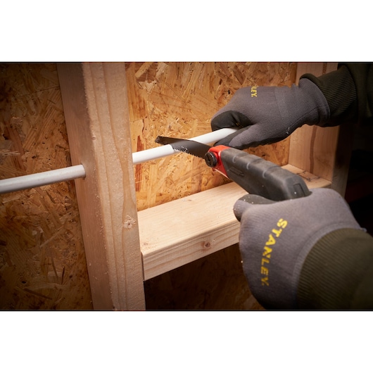 STANLEY 0-20-108 hand saw cutting white pipe, user wears Stanley gloves, photo at close angle.