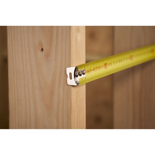 STANLEY 0-30-457 tape measure on wood, close-up angle, yellow blade with black and red markings.
