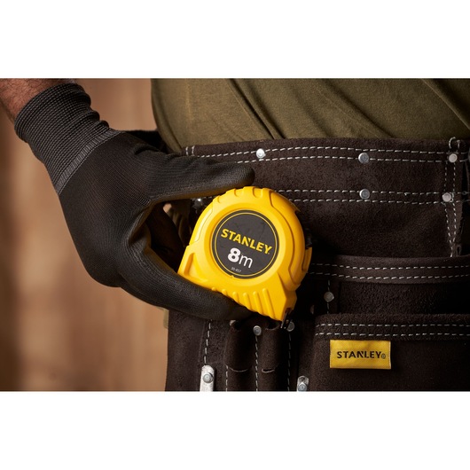 Photo of STANLEY 0-30-457 tape measure in a tool belt, held by a gloved hand.