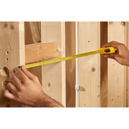 STANLEY 0-30-487 tape measure used for measuring wooden studs, close-up photography.