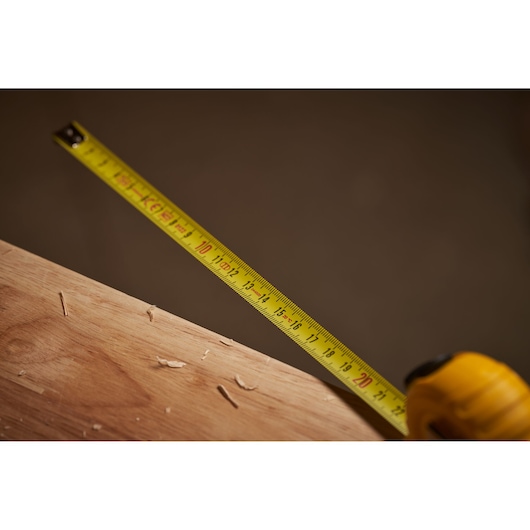STANLEY 0-30-487 tape measure extended on wood surface, yellow blade with clear markings, close-up photography.