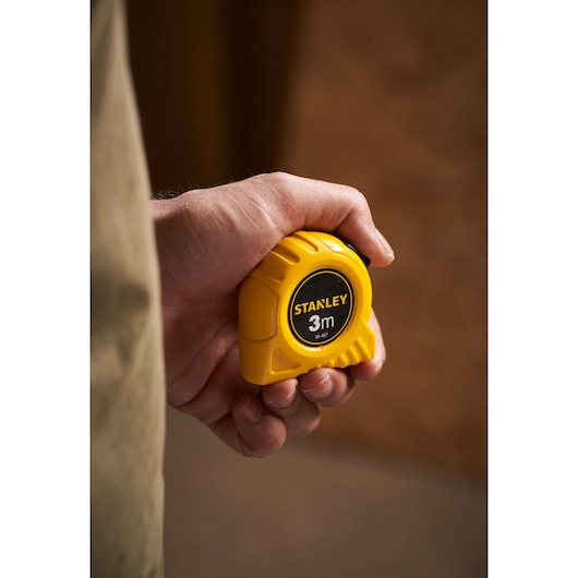 Photo of STANLEY 0-30-487 yellow tape measure, 3 meters, compact design, held in a hand.