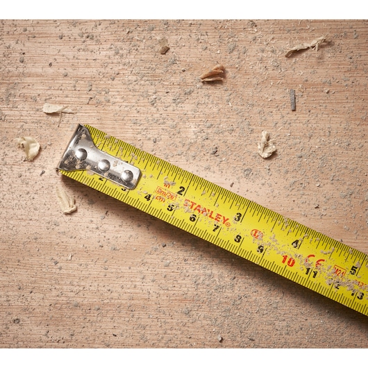 STANLEY 0-30-656 tape measure on dusty wood surface with wood shavings, close-up view.