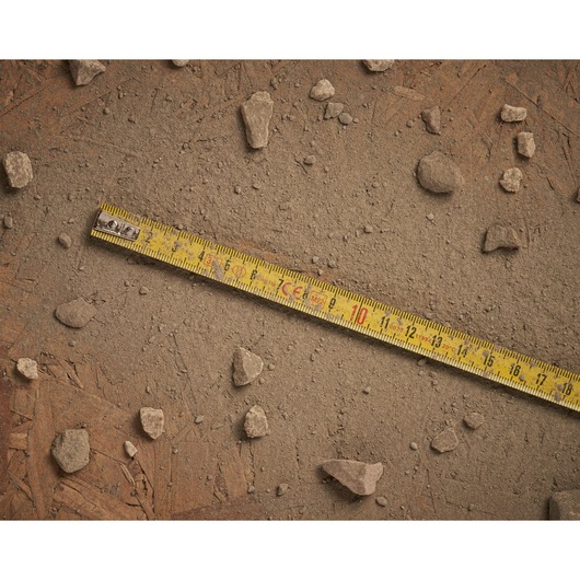 Stanley 0-32-125 yellow measuring tape on dusty ground with scattered rocks, flat angle photography.