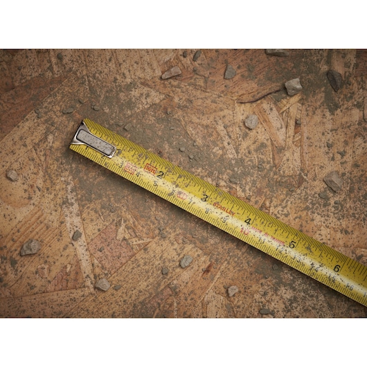 STANLEY 0-33-158 tape measure with yellow blade on dusty wooden surface, diagonal view.