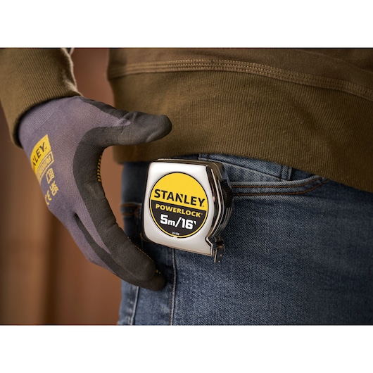 STANLEY 0-33-158 PowerLock tape measure clipped to jeans pocket, gloved hand close-up.