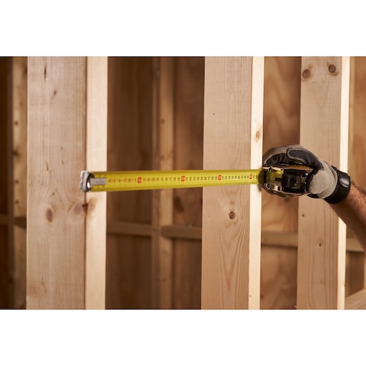 STANLEY 0-33-195 tape measure held against wooden beams, close-up during construction.