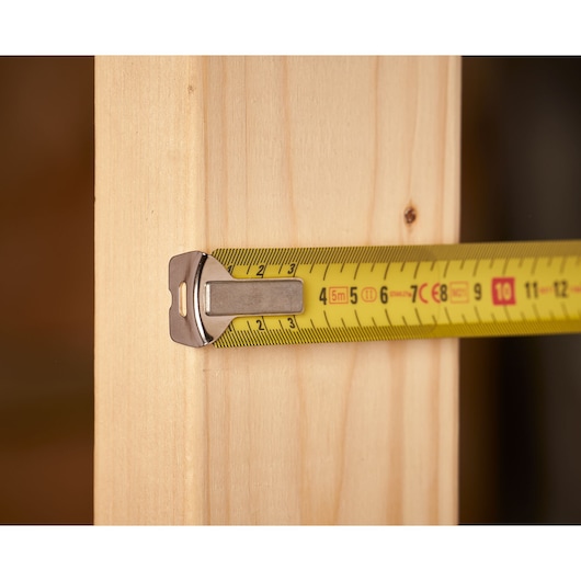 STANLEY 0-33-514 tape measure close-up, yellow tape extended on light wood surface.