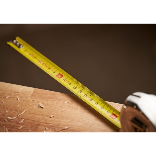 STANLEY 0-33-552 tape measure extended on wood surface with sawdust, close-up angle.