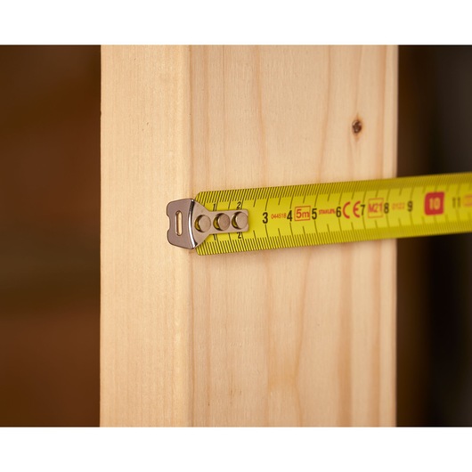 STANLEY 0-33-552 tape measure extended on wood, close-up view, yellow blade with metric markings.