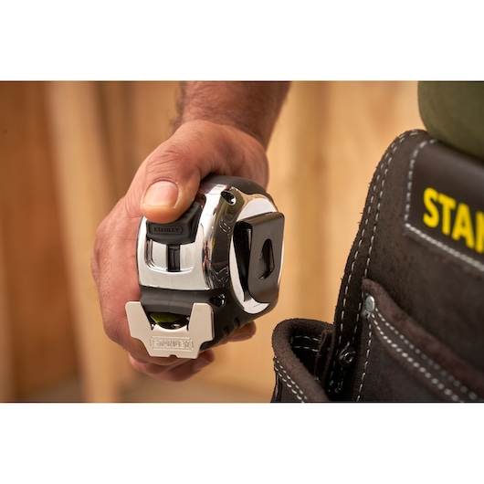 STANLEY 0-33-887 tape measure held in hand near tool belt, close-up photography.