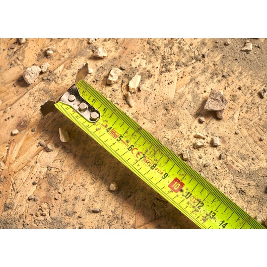 STANLEY 0-33-897 tape measure photography on dusty wood surface with rocks and debris.