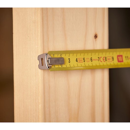 STANLEY 0-33-932 tape measure in use measuring a wooden plank, close-up view.