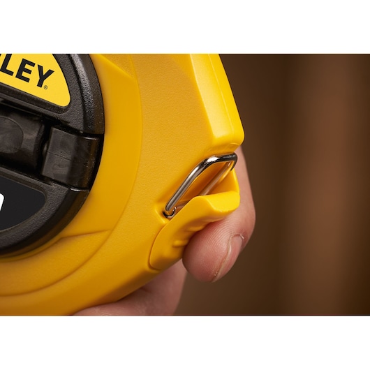 STANLEY 0-34-105 yellow measuring tape case with metal hook, close-up detail in hand.