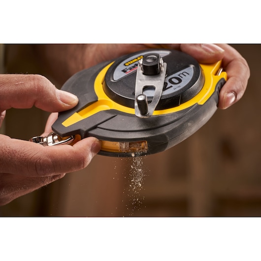 STANLEY 0-34-133 chalk line reel with yellow and black case, close-up in use, chalk powder dispensing.