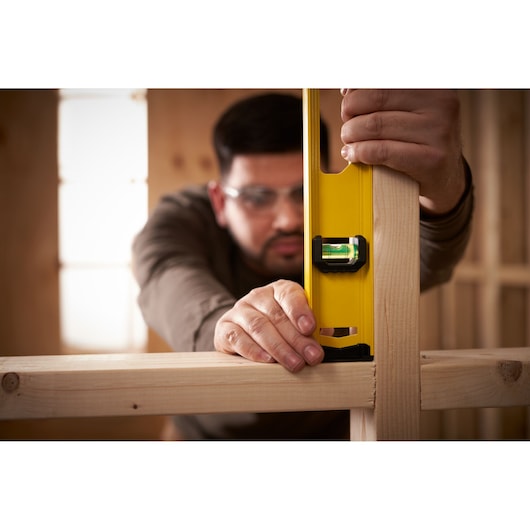 STANLEY 0-42-076 photography of yellow spirit level in use on wooden frame construction.