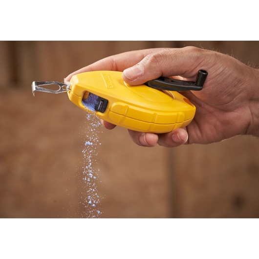 STANLEY 0-47-440 chalk line reel in yellow, hand-held with blue chalk pouring out, close-up photography.