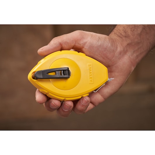 Photo of STANLEY 0-47-440 yellow chalk line reel held in hand, product category photography.