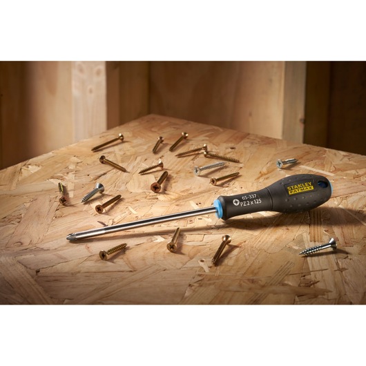 STANLEY 0-65-337 screwdriver with black handle on wooden surface, surrounded by various screws.
