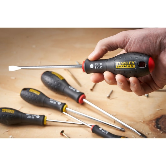 STANLEY 0-65-437 screwdriver photography, black handle with yellow logo, close-up in hand on workbench.