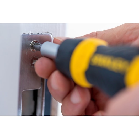 STANLEY 0-66-358 screwdriver used on a metal door plate, close-up.