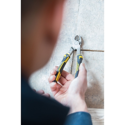 Photo of STANLEY 0-89-860 diagonal cutting pliers with black and yellow handles, held by a person on a tiled surface.