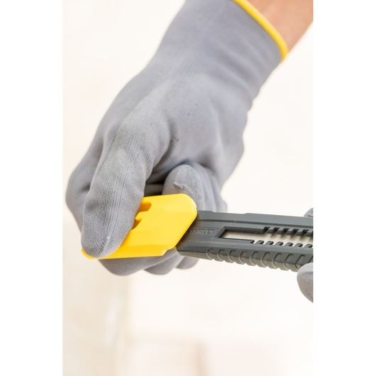 Photo of a gloved hand adjusting the yellow blade lock on a STANLEY 1-10-151 utility knife.