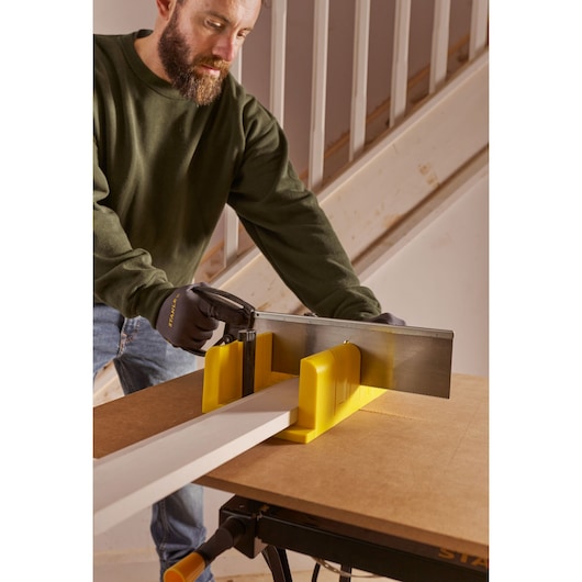 STANLEY 1-20-600 photography of yellow mitre box and saw in woodworking use, close side angle.