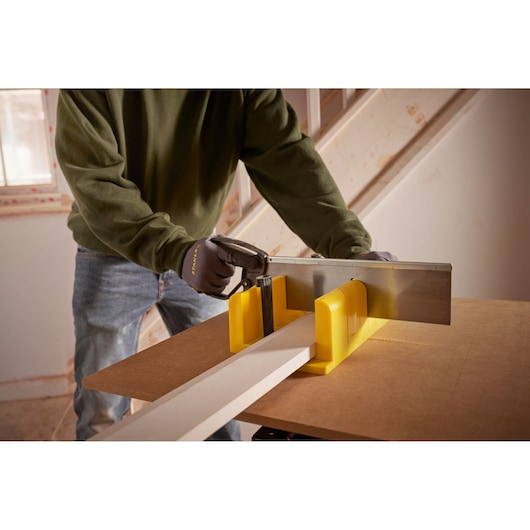 STANLEY 1-20-600 handsaw and yellow mitre box used to cut wood on a workbench, close-up angle.