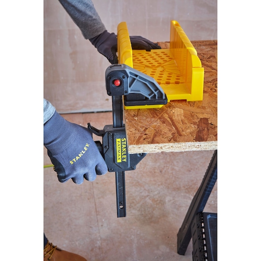 STANLEY 1-20-600 clamp holding plywood edge with yellow guide, close-up, workshop setting.