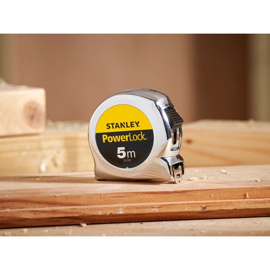 Photo of STANLEY 1-33-552 PowerLock 5m tape measure with chrome casing on wooden surface.