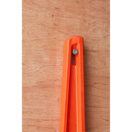 STANLEY 1-42-314 orange spirit level corner close-up photo, fixed with screw on wooden background.