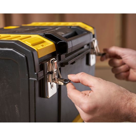 STANLEY 1-70-326 black and yellow toolbox front view with hands opening metal latches.