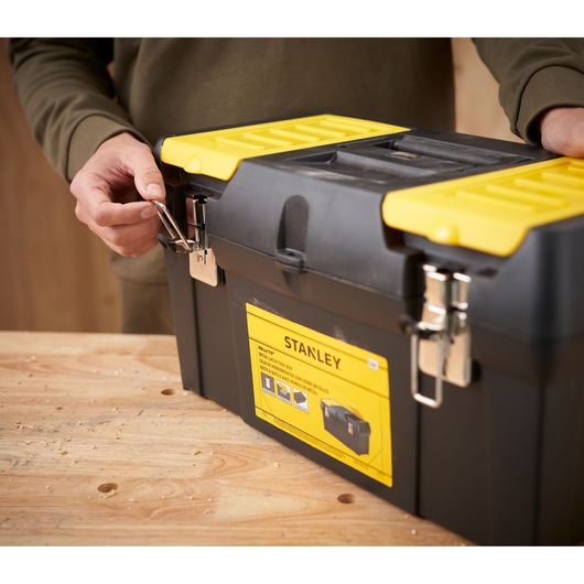 STANLEY 1-92-066 tool box with yellow lid and metal latches, front angle, on wooden table.