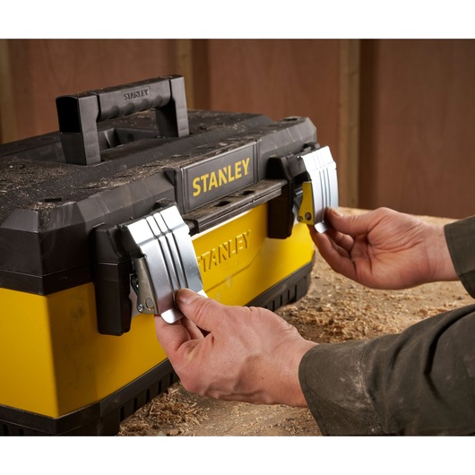 Stanley 1-95-612 toolbox with metal latches, hands opening front view, yellow and black design.