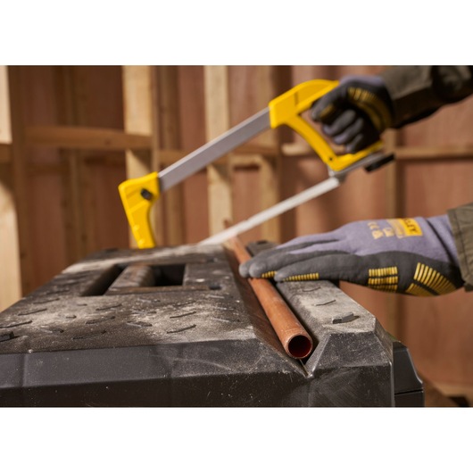 STANLEY 1-95-618 hacksaw cutting copper pipe, close-up photo, gloved hand, workshop background