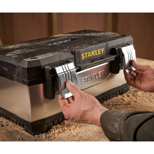 Photo of STANLEY 1-95-618 tool box with metal latches being opened, shown in workshop setting.