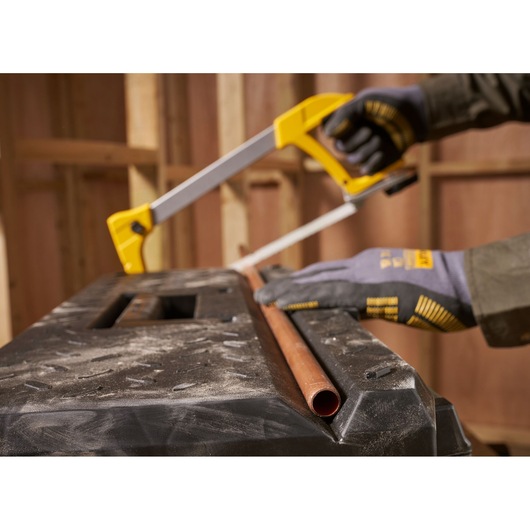 STANLEY 1-95-619 hacksaw cutting copper pipe on workbench, close-up angle, photography.