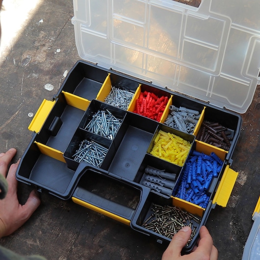 Photo of STANLEY 1-97-483 organizer box with assorted screws and colored wall plugs, top view.