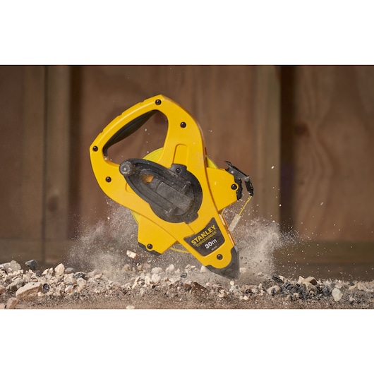 Photo of STANLEY 2-34-772 open reel measuring tape in yellow casing, in use on a construction surface.