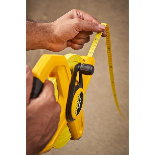Photo of STANLEY 2-34-795 yellow open reel tape measure in use, measuring distance.
