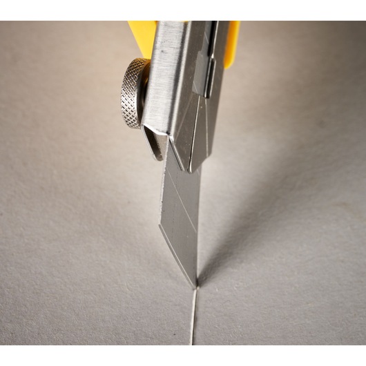 STANLEY 3-11-718 utility knife blade cutting cardboard, close-up angle.