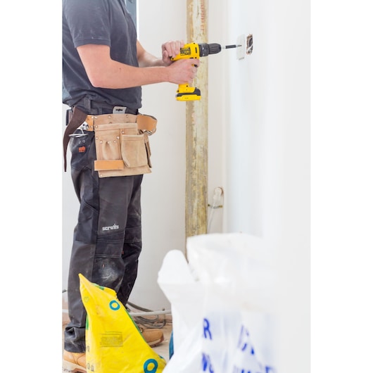 STANLEY FMC021S2 cordless drill used by worker installing outlet, indoor close-up, tool belt visible.