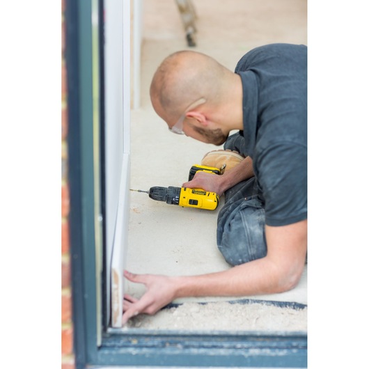 STANLEY FMC021S2 cordless drill used by person assembling white frame on floor, photography side angle.