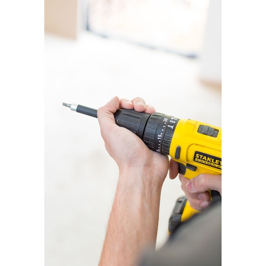 Photo of STANLEY FMC021S2 cordless drill in use, yellow and black design, close-up side angle.
