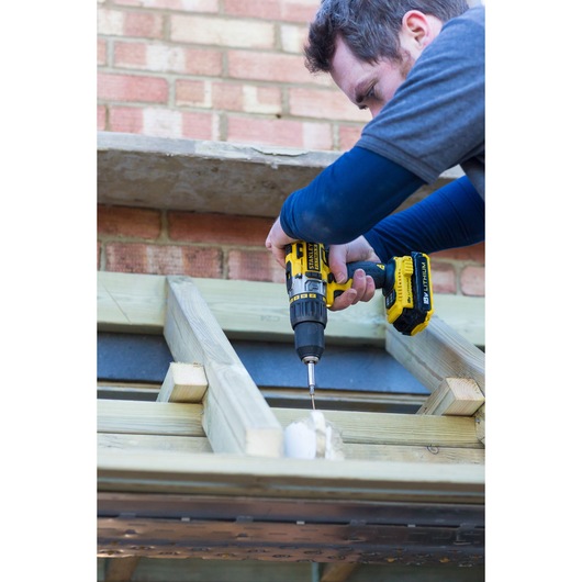 STANLEY FMC625D2 cordless drill used for wood construction, shown in outdoor work setting.