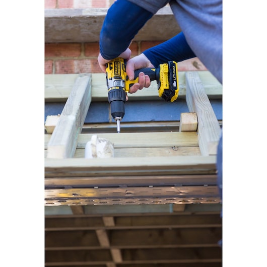 STANLEY FMC625D2 cordless drill driving screw into wooden beams, close-up of tool in use.